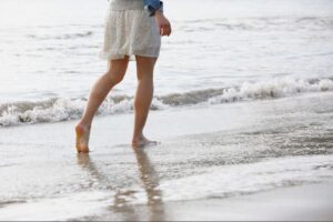Energetic Harmony Frau geht barfuß am Strand spazieren